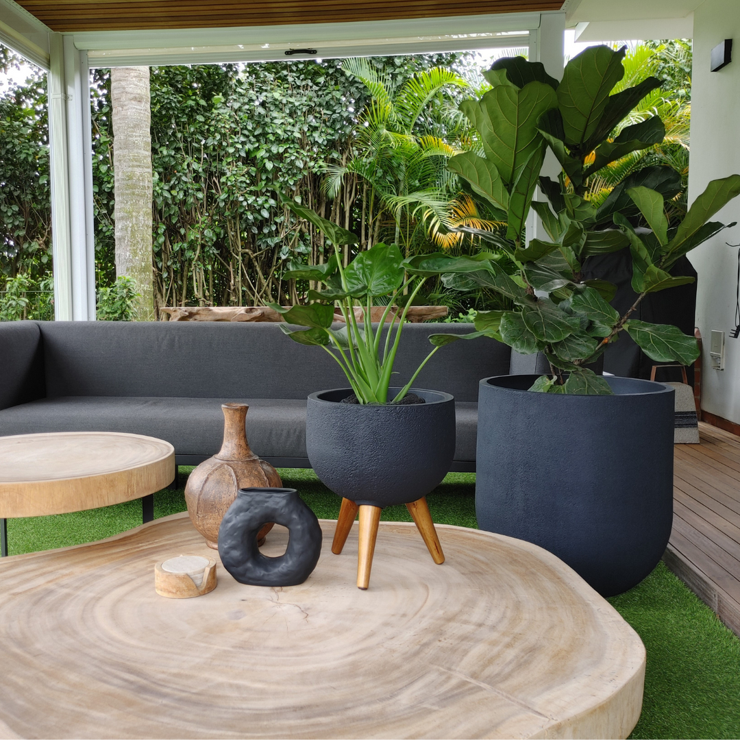 Outdoor patio with gray sofa, wooden coffee table, and potted plants