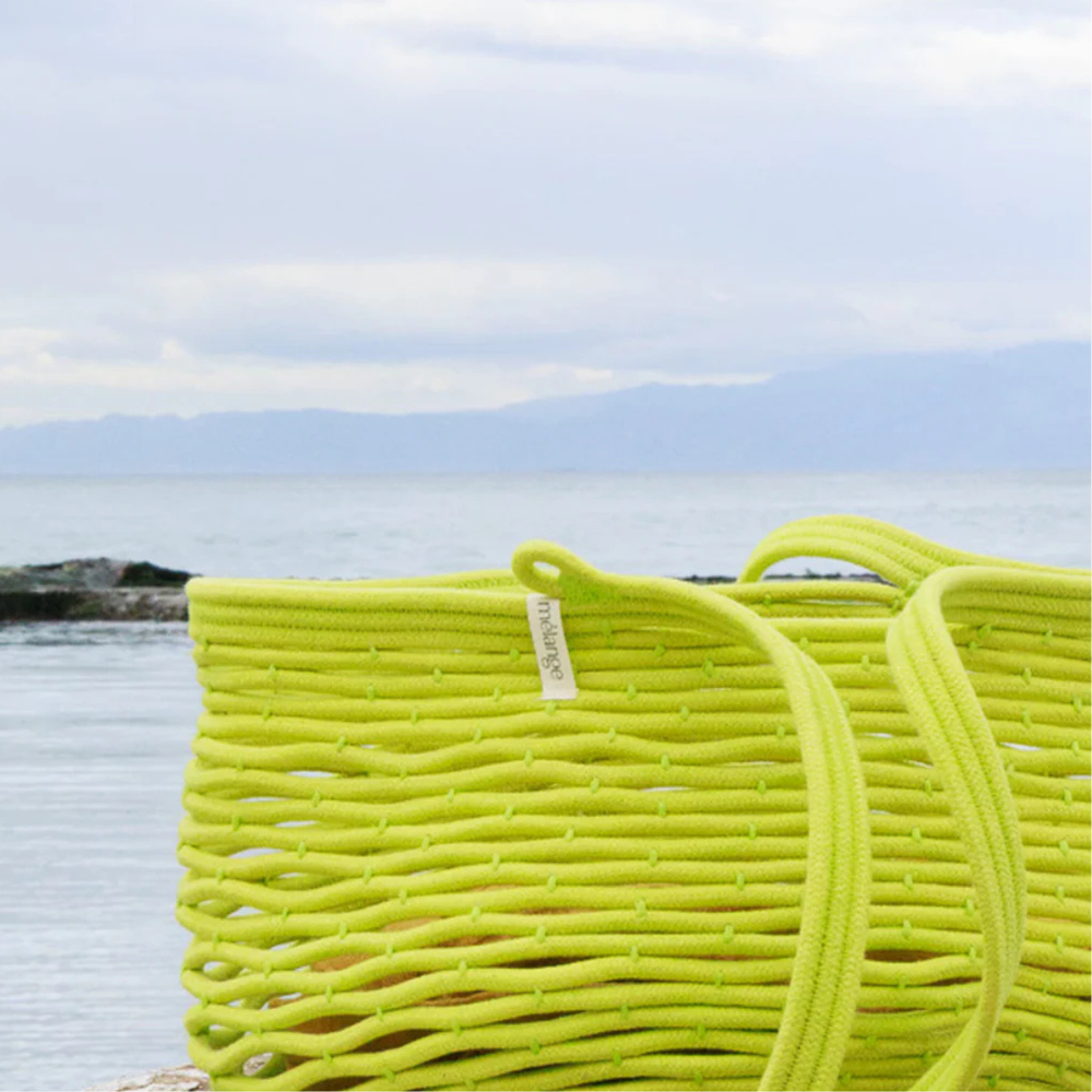 A pistachio net bag by a ocean with rocks in the background