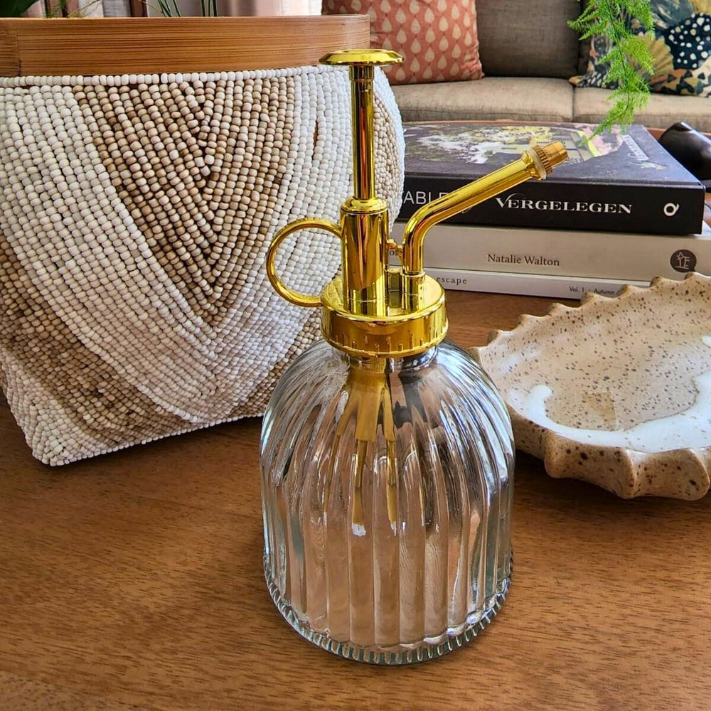 Glass spray bottle with gold nozzle on a wooden surface