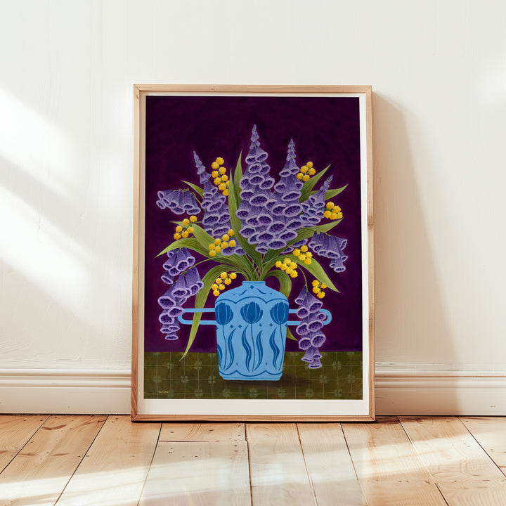Framed artwork of a blue vase with purple flowers and yellow buds on a white wall.