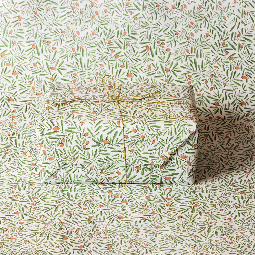 Gift box wrapped in a olive and foliage patterned paper on a matching background.
