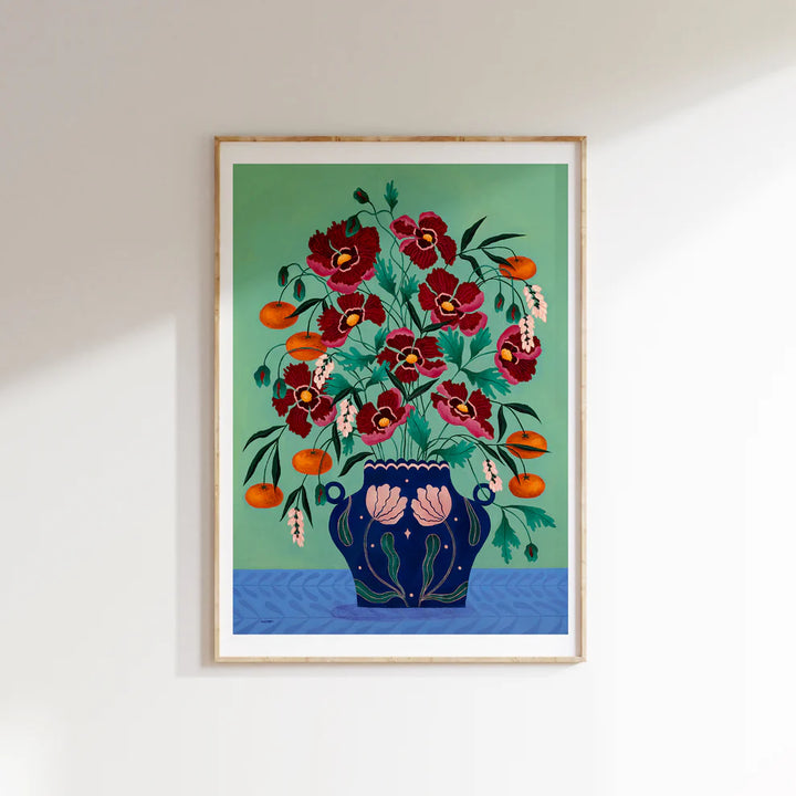 Framed Fine art print of a bright red floral display in a deep blue vase with light pink floral motif.