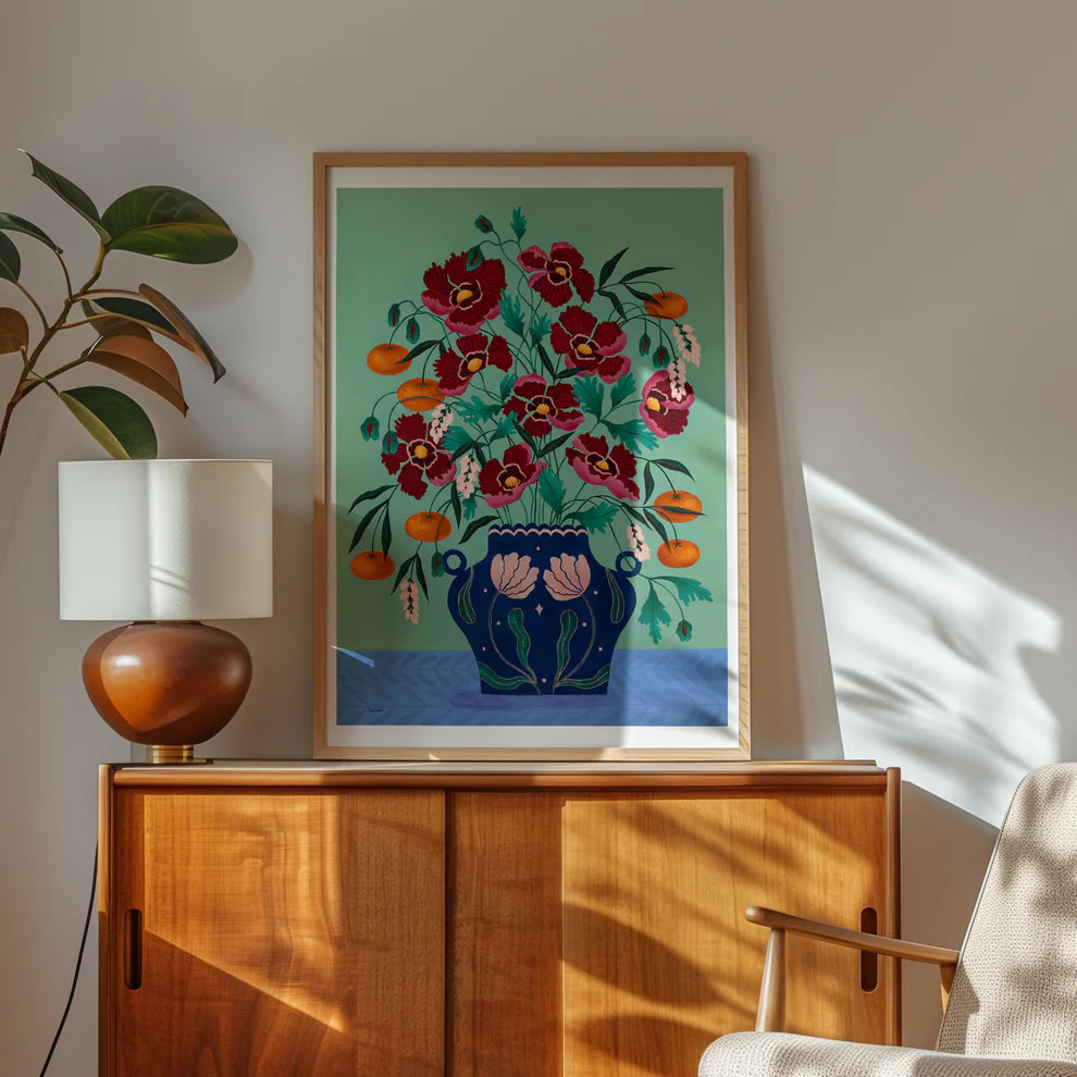 Framed Fine art print of a bright red floral display in a deep blue vase with light pink floral motif.